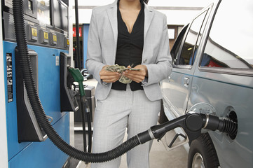 Mid section of a woman counting money while waiting for refueling car