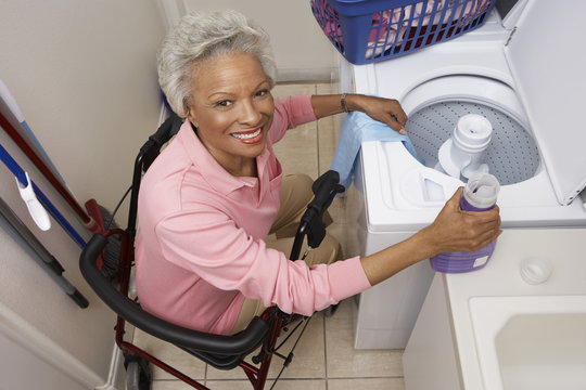 Portrait of a disabled African American woman sitting on wheel chair by washing machine