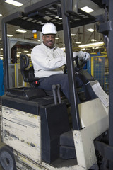 Fototapeta na wymiar Portrait of a smiling man sitting in forklift truck at newspaper factory