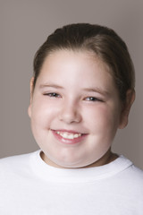 Closeup of an overweight girl smiling against gray background