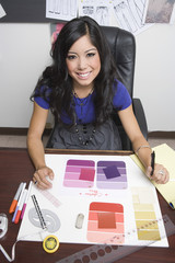 Portrait of a smiling female fashion designer working at desk