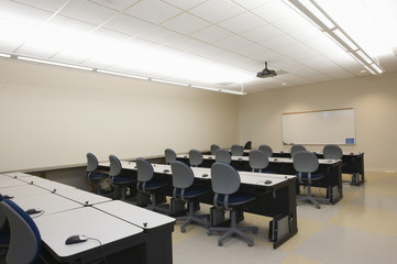 Empty chairs and tables in front of whiteboards in seminar room