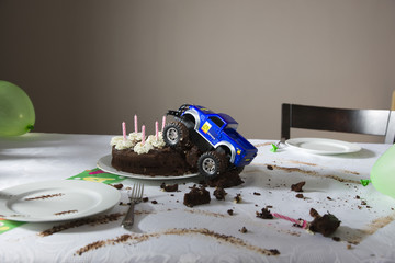 Closeup of a toy car driven into birthday cake on table at home