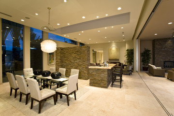 Dining area against kitchen with living room in background at modern house