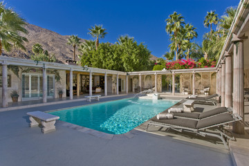 Sunloungers by swimming pool in the house courtyard against clear blue sky
