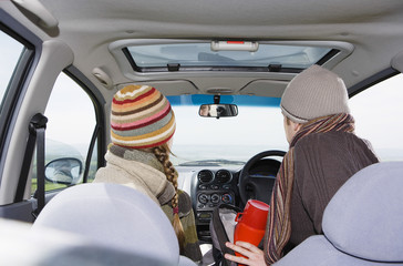 Rear view of young couple wearing warm clothing in car during road trip
