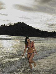 Happy young bikini woman walking in water at the beach