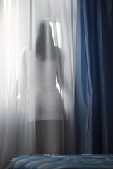 Fototapeta na wymiar Rear view of a woman looking through window at home
