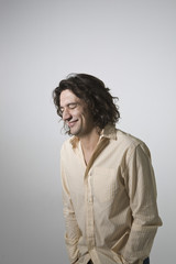 Smiling young man with eyes closed standing against gray background