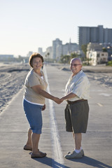 Fototapeta premium Happy senior Caucasian couple holding hands on promenade