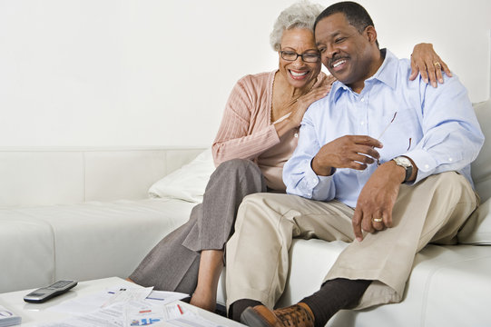 Happy African American Senior Couple Sitting On Sofa At Home
