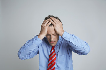 Depressed entrepreneur with hands on head isolated over grey background