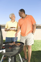 Happy African American couple looking at each other while barbequing in lawn