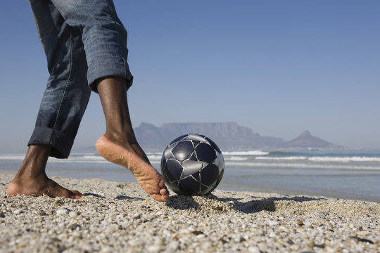 Lowsection of a man playing soccer on beach