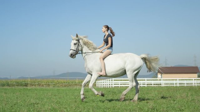 SLOW MOTION: Young woman running bareback with her beautiful white horse