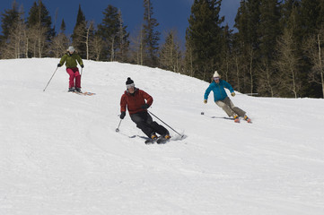 Three skiers skiing down slope on a snow capped mountain