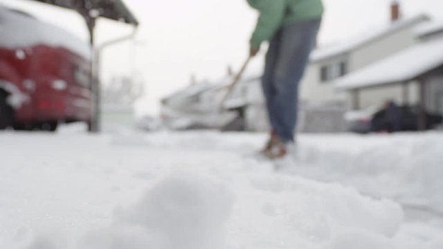 CLOSE UP: Male worker shoveling fresh snow from the front yard and making pile