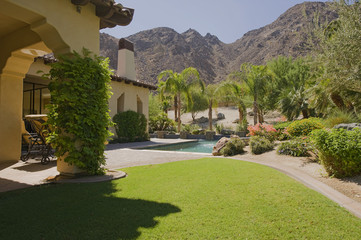 Obraz premium House exterior with swimming pool in garden and mountains in background