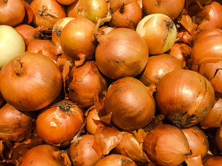  Fresh organic onion stand out among many large background yellow onions in the market. Heap of...