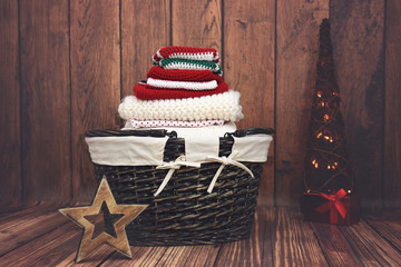 Red, white and green knit Christmas clothes in a wicker basket with Christmas tree - 129962666