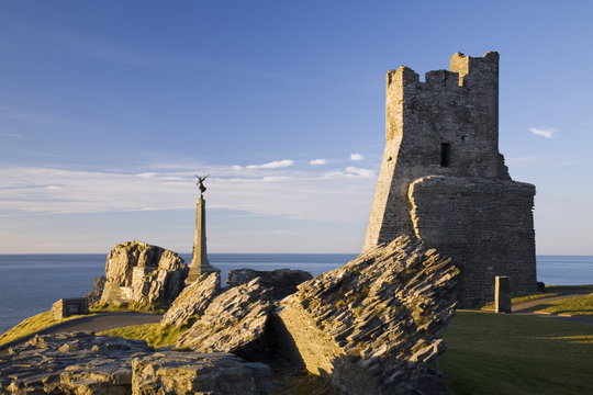 Ruins of 13th century castle and remains of Porth Newydd (New Gate) on Castle Point with War Memorial and sea beyond in low winter light, Aberystwyth, Ceredigion, Dyfed, Wales