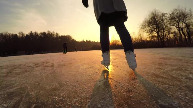 CLOSE UP: Unrecognizable young woman iceskating fast on big icy pond in park