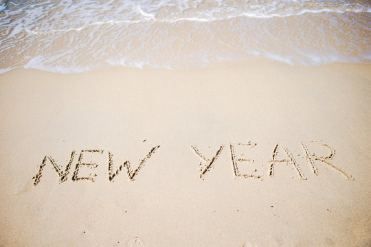 Happy New Year written in the white sand