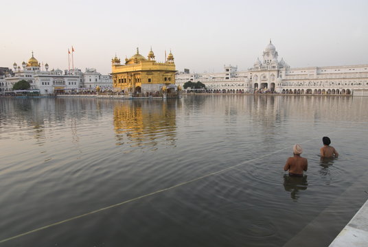 Two Sikh pilgrims bathing and praying in the early morning in holy pool, Golden Temple, Amritsar, Punjab state
