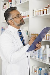 Male pharmacist noting the names of medicines at pharmacy