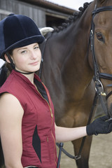 Obraz premium Portrait of a young woman in riding hat with a horse outdoors