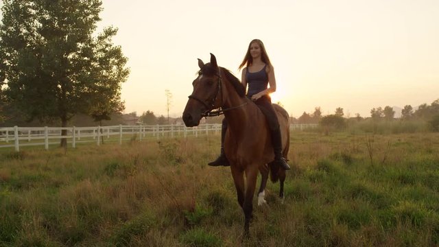 SLOW MOTION: Happy young blonde girl bareback riding on misty summer morning