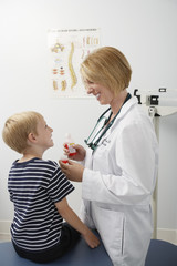 Obraz premium Happy female doctor giving medicine to a boy in the clinic