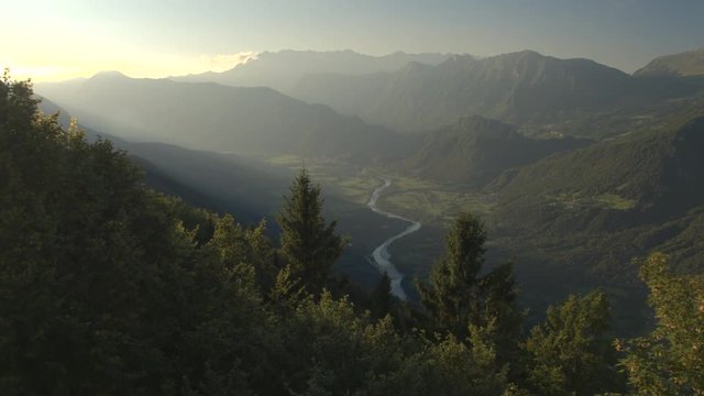 AERIAL: Meandering river winding through mountain valley in misty morning