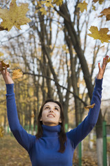 Obraz premium Young woman under falling leaves in the park