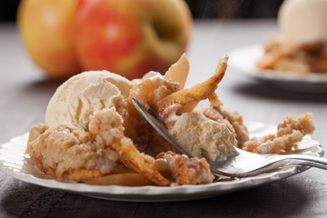 Horizontal view of large dish of apple crisp with vanilla ice cream on top