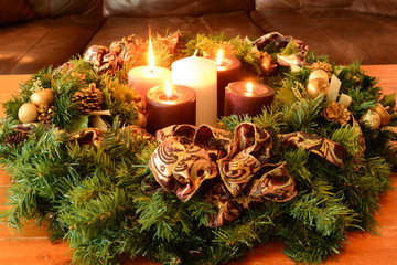 Traditional Advent wreath on rustic table with candles glowing warm