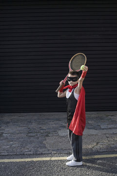 Full length of a young boy in Zorro costume with tennis racket