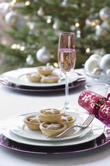 Christmas mince pies, cracker and champagne flute on dining table