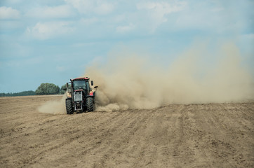 Naklejka premium Tractor plowing dry farm land at autumn