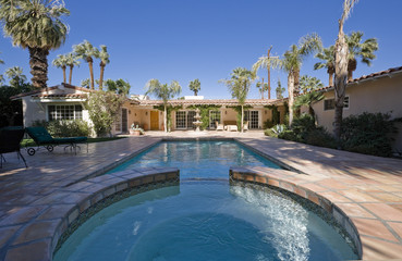 Swimming pool at the backyard of a modern home against clear blue sky