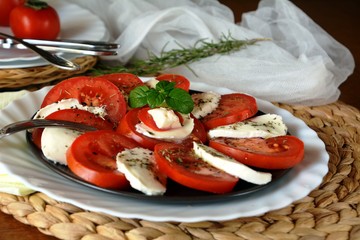 Fresh healthy vegetable salad with mozzarella, tomato and basil on a plate