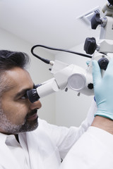 Naklejka na ściany i meble Closeup of an Asian male dentist using microscope in clinic