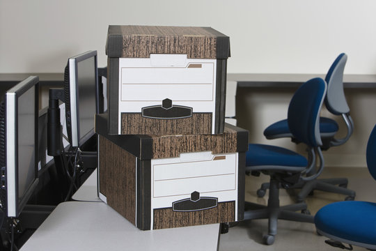 View of moving boxes by chairs on office desk