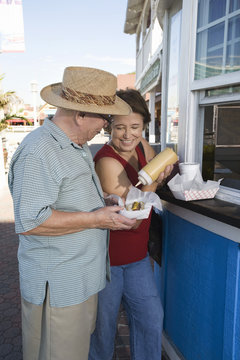 Happy Couple Eating Hot Dog At Food Stand