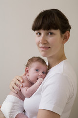 Side view of a mother hugging her newborn baby against colored background