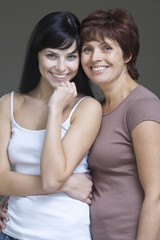 Portrait of a smiling young woman with her mother against gray background