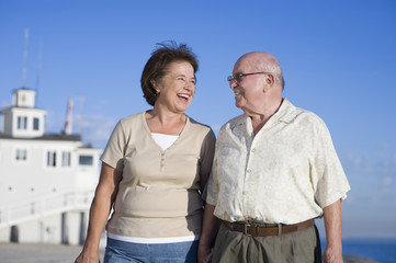 Happy romantic senior Caucasian couple looking at each other against clear blue sky