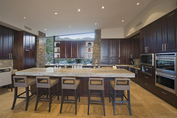 View of a spacious kitchen with stools at the island in modern house