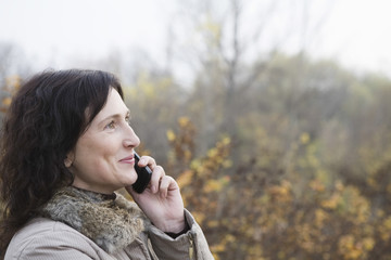Closeup side view of a woman using mobile phone outdoors