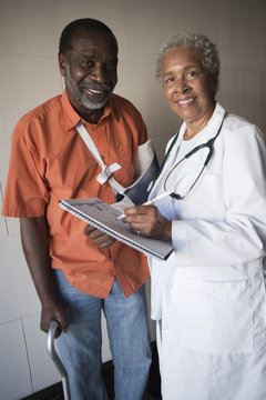 Portrait of African American female doctor standing with disabled patient in hospital